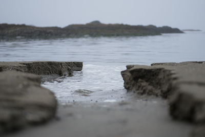 Close-up of rocks in river against sky