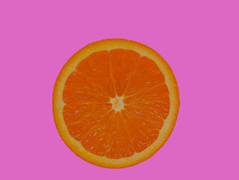 Close-up of orange slice against pink background