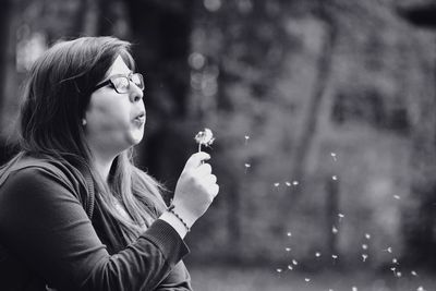 Close-up of woman blowing dandelion