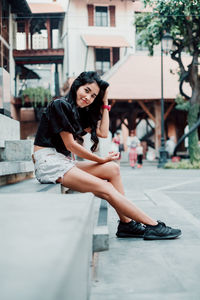 Full length portrait of woman sitting outdoors