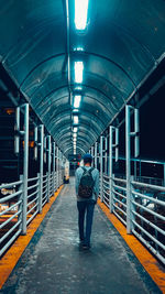 Rear view of man standing on illuminated walkway