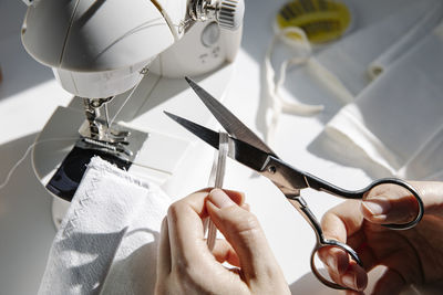 Tailor woman cutting elastic band for handmade fabric mask at home