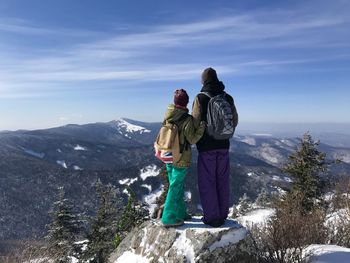 Rear view of people walking on snow covered mountain