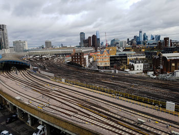 High angle view of railroad tracks in city against cloudy sky