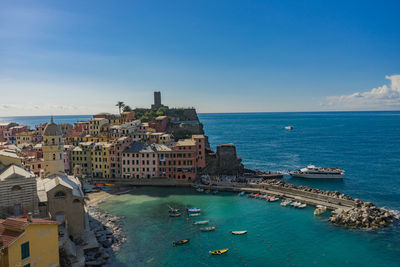 High angle view of buildings by sea against blue sky