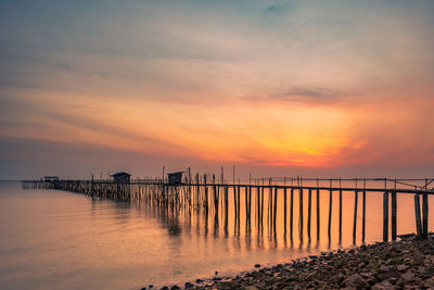 Pier on sea against sky during sunset