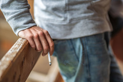 Midsection of man holding cigarette