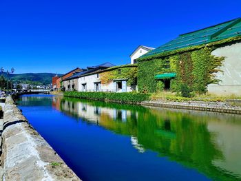 Reflection of building on lake against blue sky