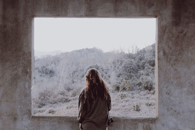 Rear view of woman standing in window