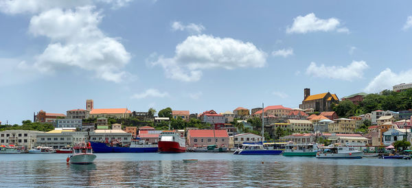 Sailboats moored in river by town against sky