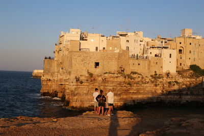 People standing by sea against clear sky