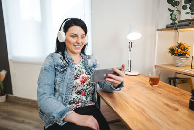 Young woman using mobile phone while sitting at home