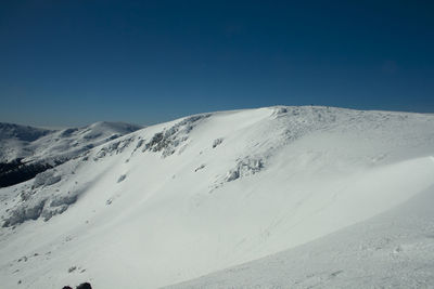 Scenic view of snowcapped mountains against clear blue sky