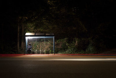 Light trails on road against trees at night