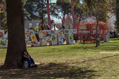 People sitting on tree trunk by plants