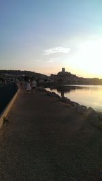 People at sea shore against sky during sunset