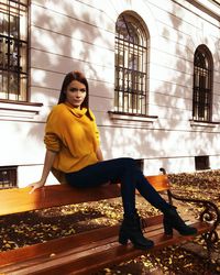 Young woman sitting on chair against building