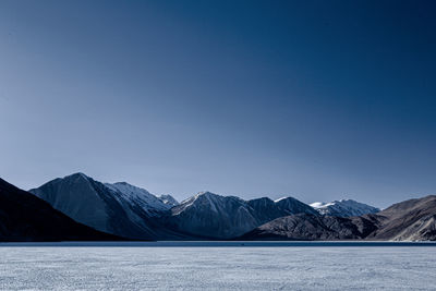 Scenic view of snowcapped mountains against clear blue sky