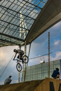 Low angle view of man riding bicycle against sky