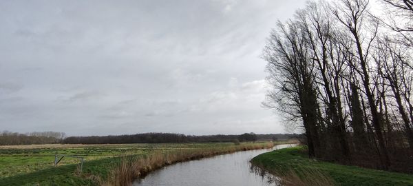 Scenic view of canal amidst field against sky