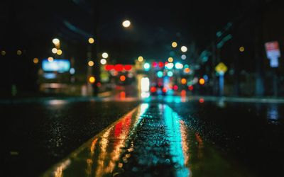 Surface level view of wet street against illuminated city