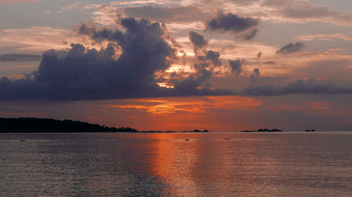 Scenic view of sea against dramatic sky during sunset