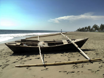 Boat moored on beach against sky