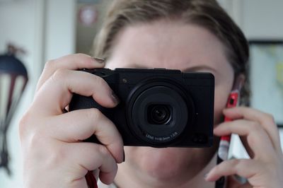 Close-up of woman photographing through camera while talking on mobile phone