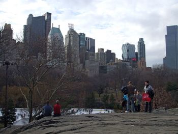People on rock against sky in city