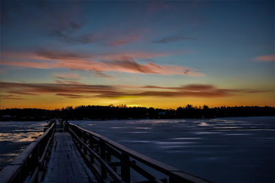 Scenic view of lake against dramatic sky during sunset