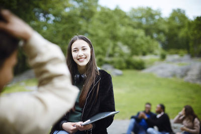 Smiling female teenager looking at man in park