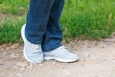 Men's legs in bright sneakers stand on road in park against the background