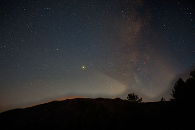 Low angle view of silhouette mountain against sky at night