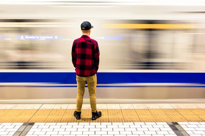 Rear view of man standing at railroad station