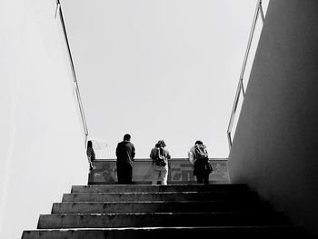 Low angle view of people on stairs against clear sky