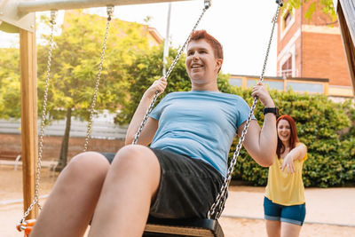 Happy woman pushing friend on swing