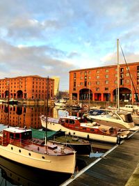 Boats moored at harbor against sky in city