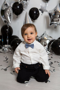 Boy in black clothes on his birthday party with balloon and silver stars