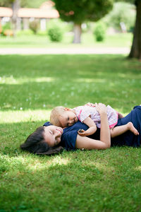 High angle view of siblings lying on grassy field