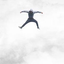 Low angle view of man jumping against sky