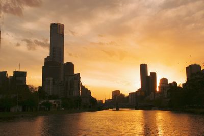 Modern buildings in city against sky during sunset