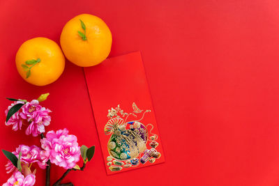 High angle view of orange flower on table against red background