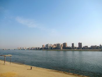 Sea by buildings against sky in city