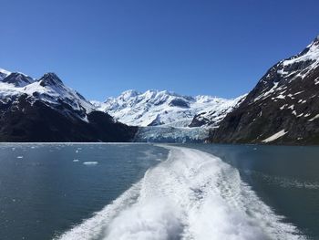 Wake in sea by snowcapped mountains