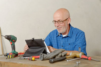 Smiling carpenter using digital tablet at desk in workshop