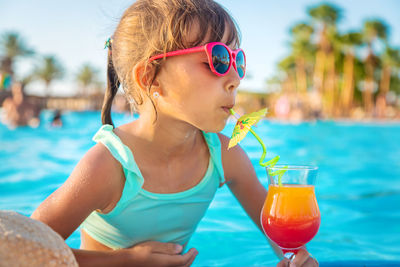 Low section of woman holding drink at beach