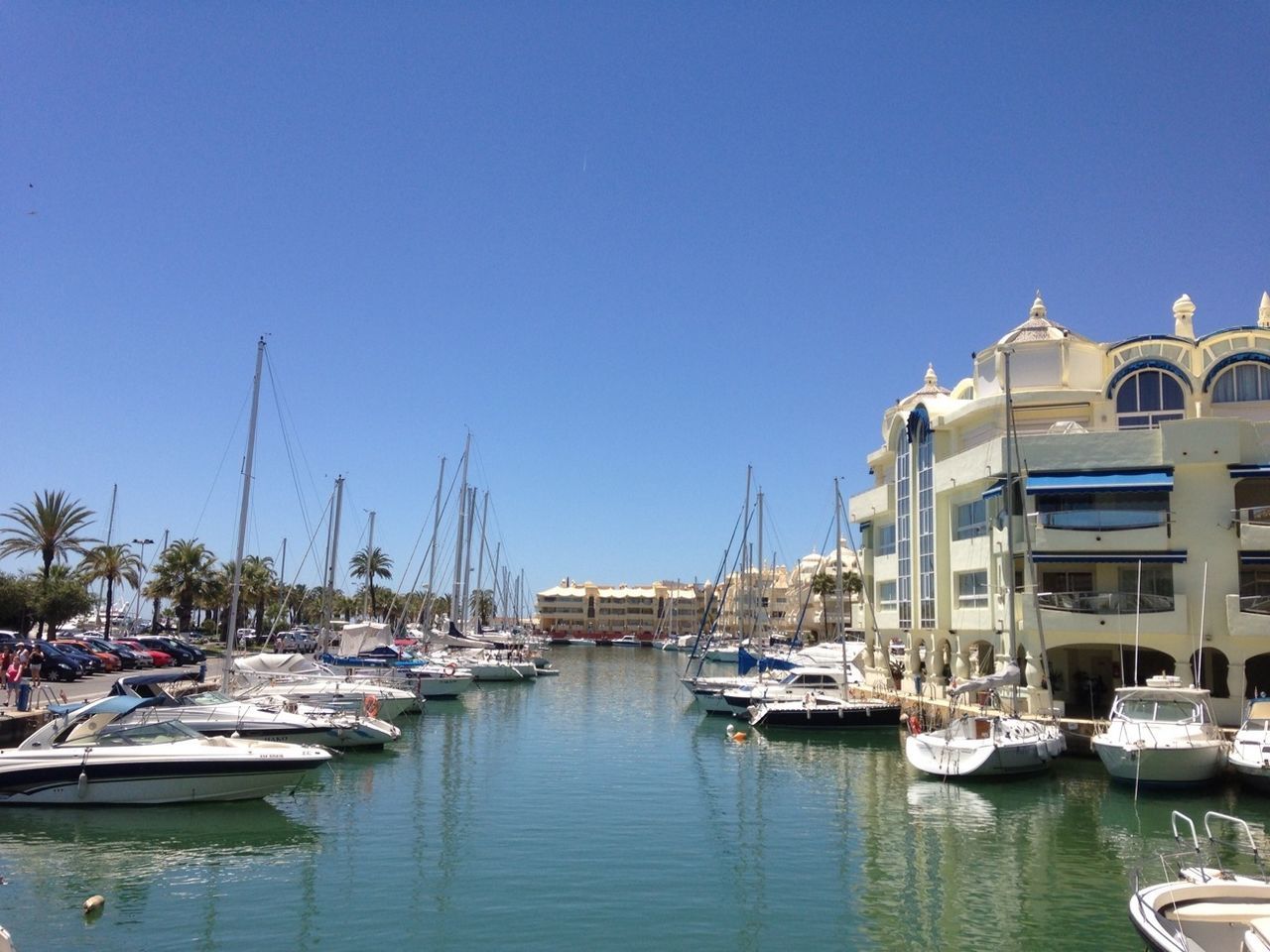 nautical vessel, boat, moored, transportation, mode of transport, water, clear sky, building exterior, blue, waterfront, copy space, mast, sailboat, harbor, built structure, architecture, sea, reflection, day, travel