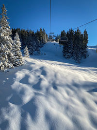 View of snow covered landscape saalbach-hinterglemm seen from chairlift against blue sky