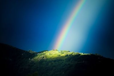 Rainbow over mountain against blue sky