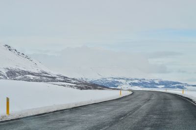 Road amidst snowcapped mountains against sky